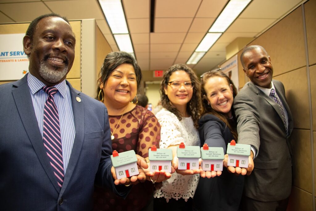 Left to Right: Mayor Jerry Demings, Commissioner Uribe, Commissioner Bonilla, Commissioner Wilson, Commissioner Scott smiling holdings tiny stress balls in the shape of a house