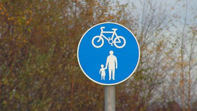Street sign of bicycle and adult holding child's hand