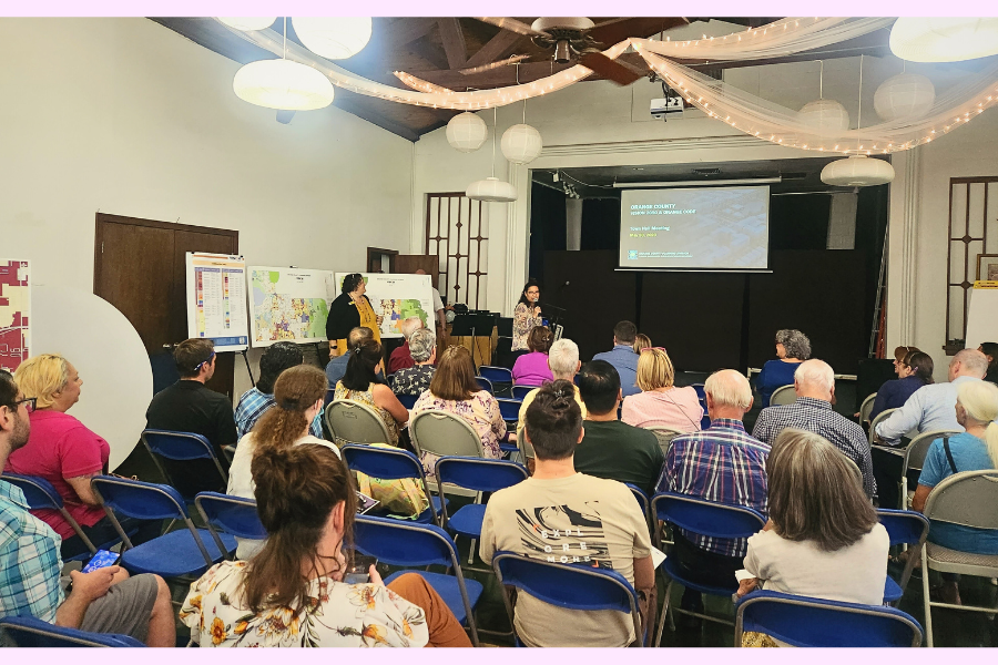 Commissioner Emily Bonilla standing and speaking to a group of around 25 people during the Vision 2050 event. The audience is seated and attentive as she delivers her address.