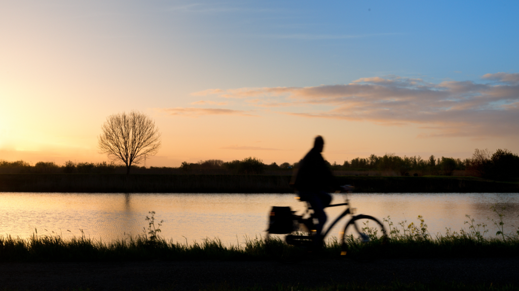 Photograph of a silhouette biking on a trail during sunset