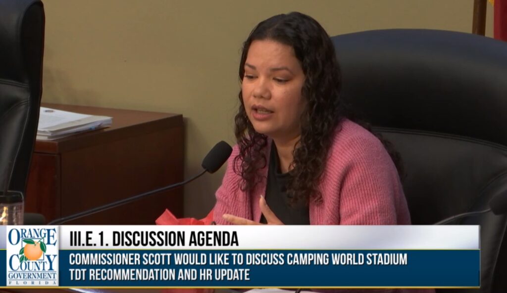 Commissioner Emily Bonilla pictured speaking about the discussion agenda item with text that reads "Commissioner Scott would like to discuss Camping World Stadium TDT Recommendation and HR Update."