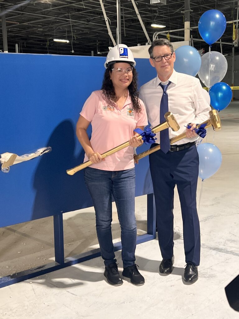 Commissioner Emily Bonilla poses for a photo with representative of Goodwill Industries. Both hold a golden sledgehammer ceremony.
