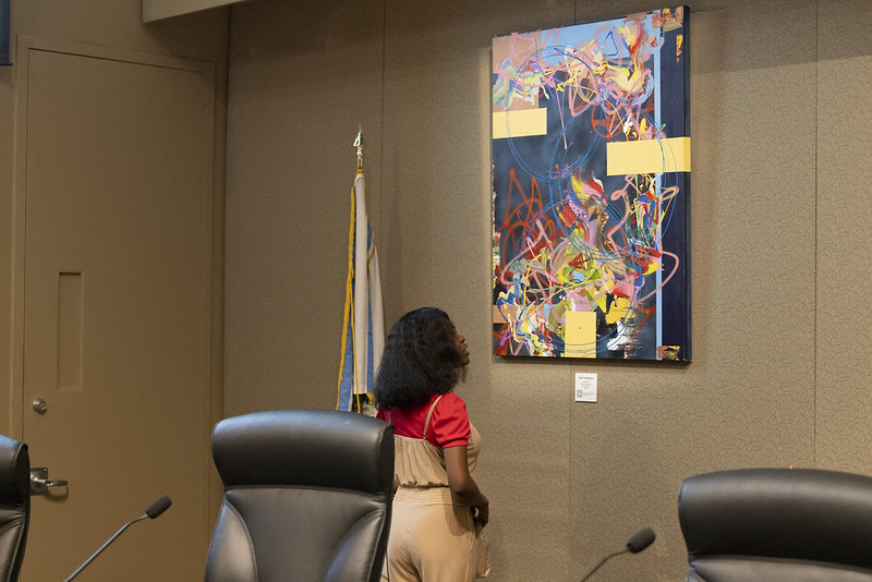 photograph of a young woman admiring a piece of art in the county commission chambers