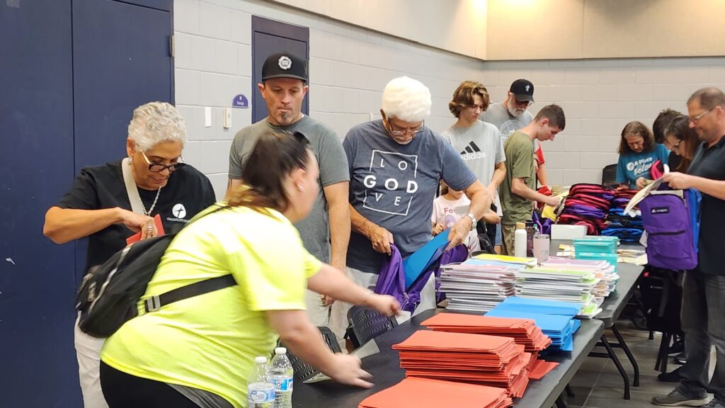 photograph of volunteers packing backpacks for the backpack giveaway.