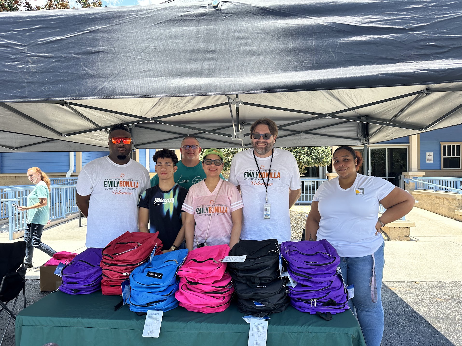 photograph of commissioner Bonilla with the team working the backpack giveaway